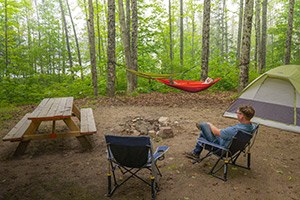 Campers enjoy the peaceful setting of a Boney Falls camp site from hammocks and relaxing chairs.