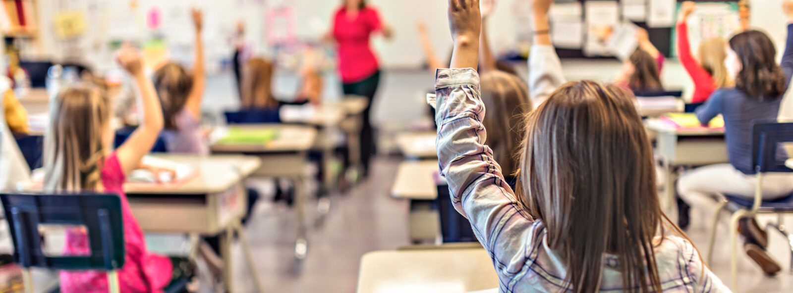 kids in a classroom with hands raised