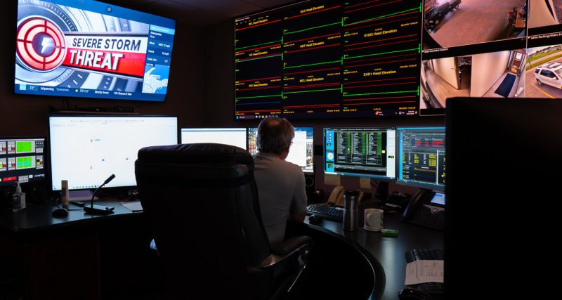 A man sits behind many screens within the System Operations Center