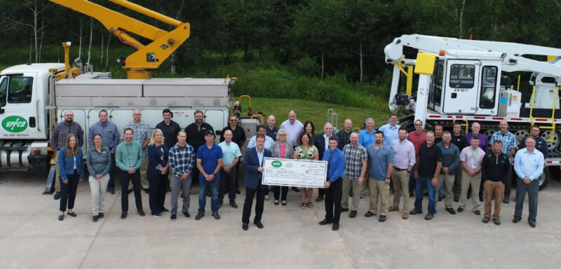 UPPCO CEO Jim Larsen (left) presents a check to United Way Executive Director Andrew Rickauer (right), surrounded by UPPCO employees.