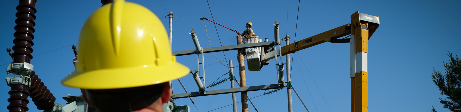 UPPCO lineman at work on overhead lines with another looking on from below