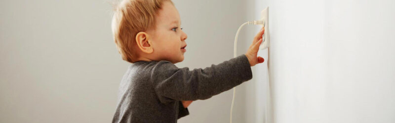 small child reaching for electrical outlet and plug