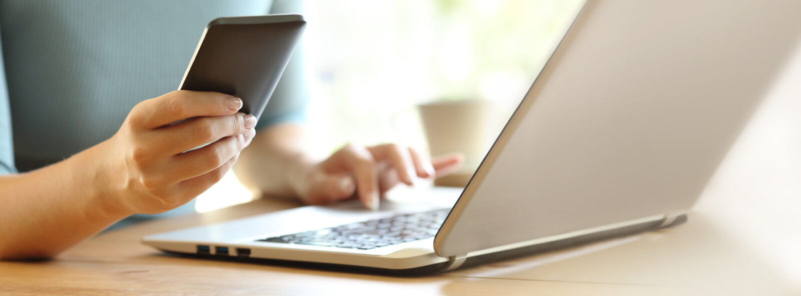 close up of a person using a laptop and holding cell phone